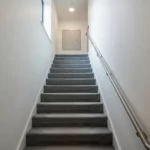 Clean carpeted communal stairwell leading to a flat in a Peterborough building, maintained by DustBlasters