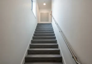 Clean carpeted communal stairwell leading to a flat in a Peterborough building, maintained by DustBlasters